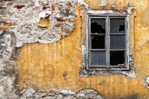 Broken window on a weathered yellow wall