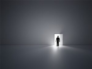 Glowing open doorway in a vast empty grey room