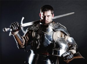 Medieval knight in armour holding a sword on his shoulder